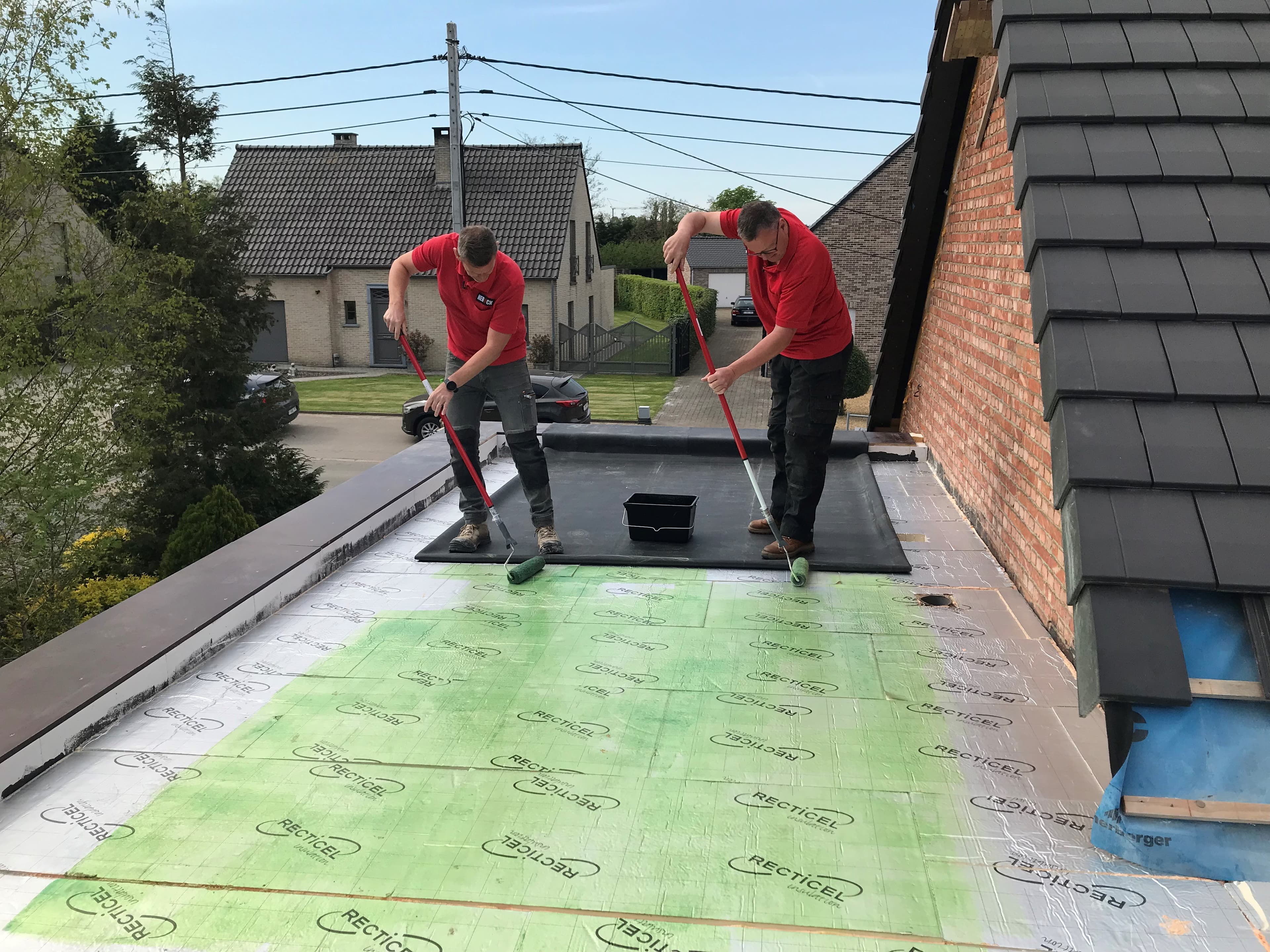Twee dakwerkers brengen RoofCover contactlijm aan op een EPDM-dak